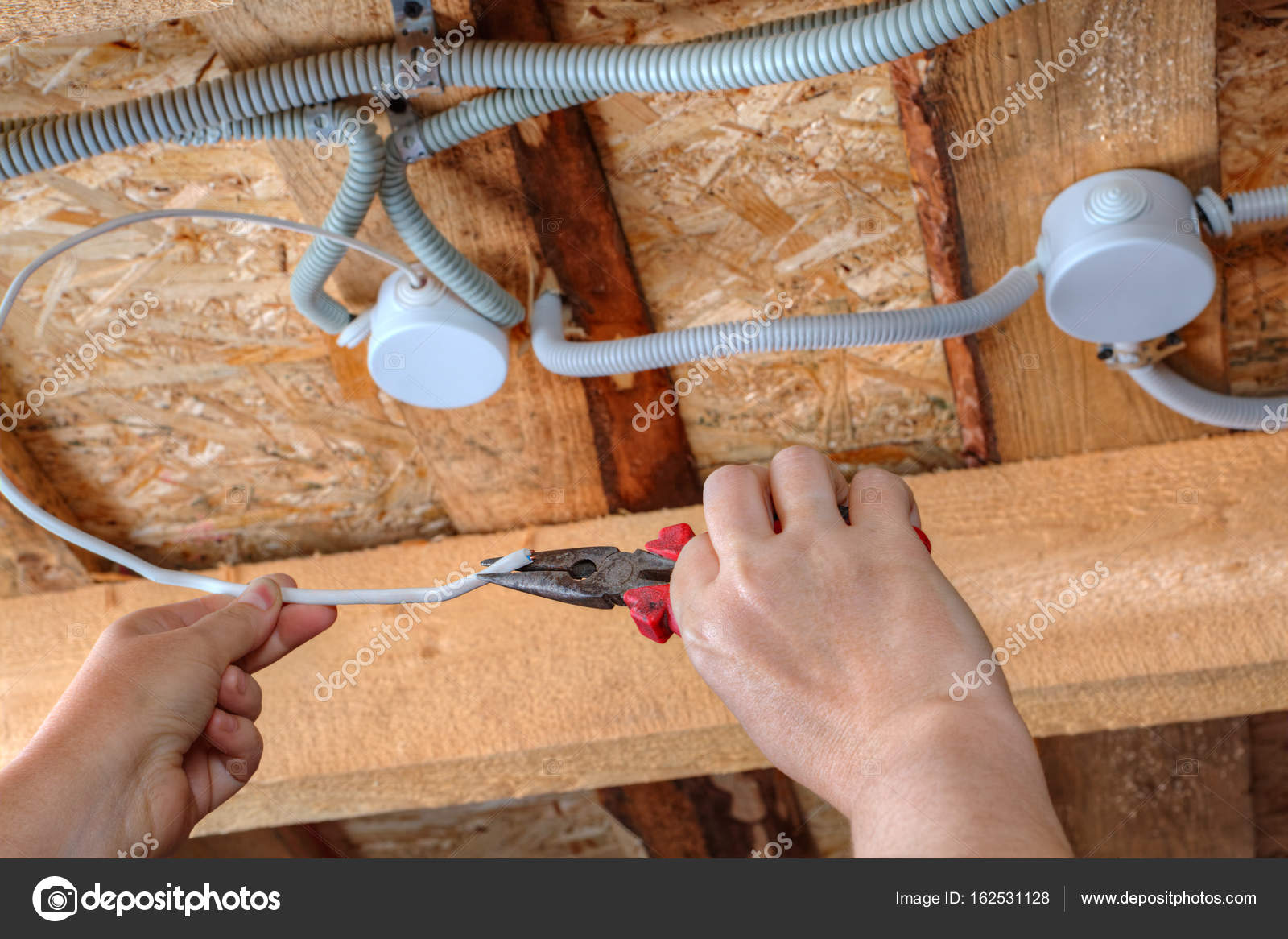 Hands Of Electrician With Pliers During Working On Ceiling Wires