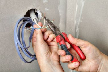 Elektrikçiler temizler kullanarak pense, eller yakın tellerin uçları-
