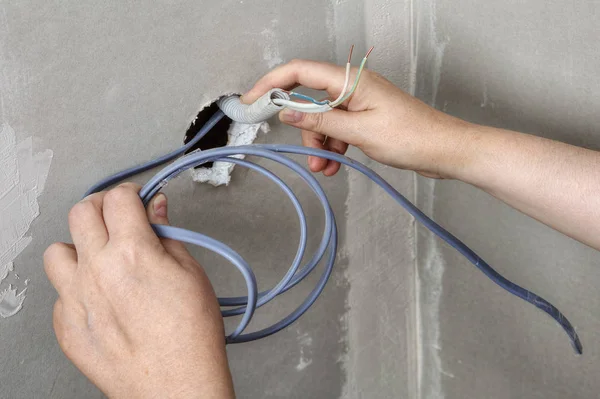 Pulling wires through wall hole, electrician hands close-up. — Stock Photo, Image