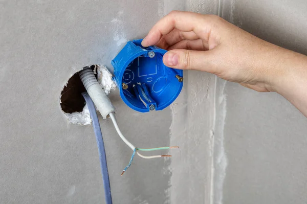 Instalar caixa elétrica no buraco da parede, mão close-up . — Fotografia de Stock