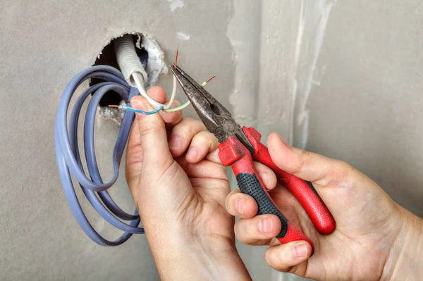Eletricistas limpa as extremidades dos fios usando alicates, mãos fechadas - — Fotografia de Stock