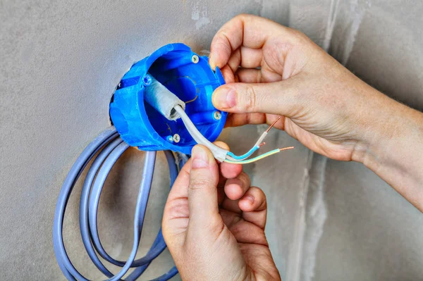 Close-up van een hand zet de elektrakast vast op de muur. — Stockfoto