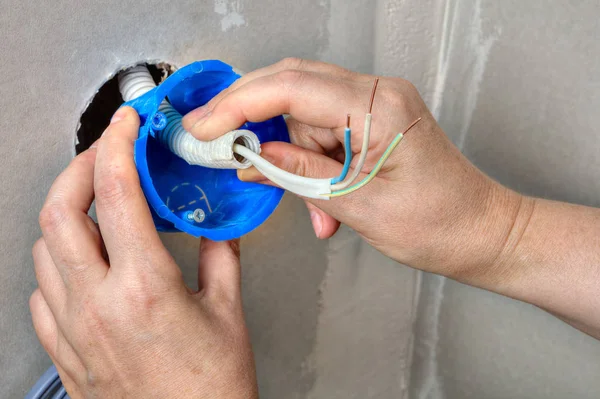 Hands electrician fix electricity round plastic outlet box on wa — Stock Photo, Image