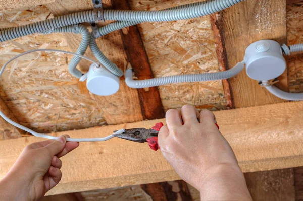 Mãos de eletricista com alicate durante o trabalho em fios de teto — Fotografia de Stock