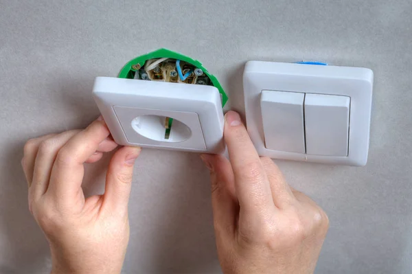 Instalación de la salida de la pared en una caja de cableado, manos de cerca . — Foto de Stock