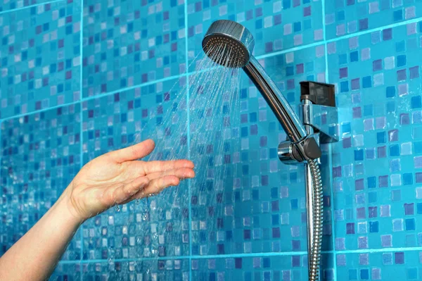 Hand being sprayed with water from the shower head.