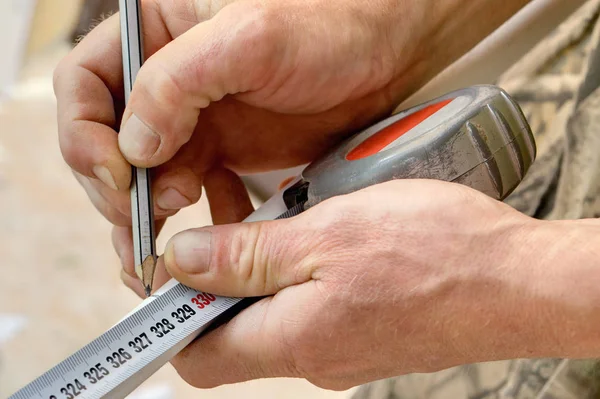 Homme marquant morceau de tuyau à l'aide de crayon et ruban à mesurer . — Photo