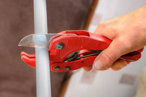 Hands plumbing with a cutter for plastic pipes. — Stock Photo, Image