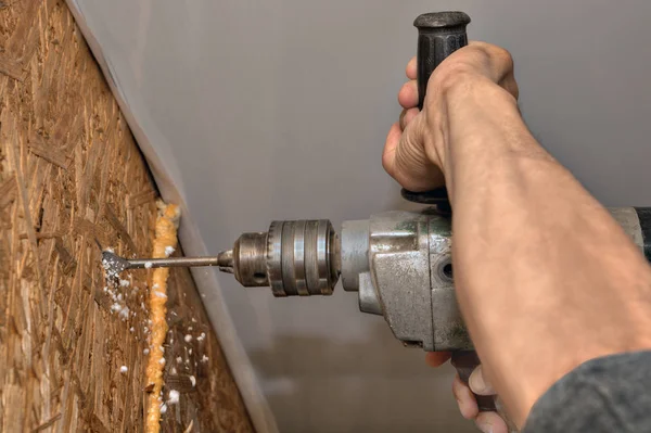 Close-up van handen werknemers houten muur boren met een boor. — Stockfoto