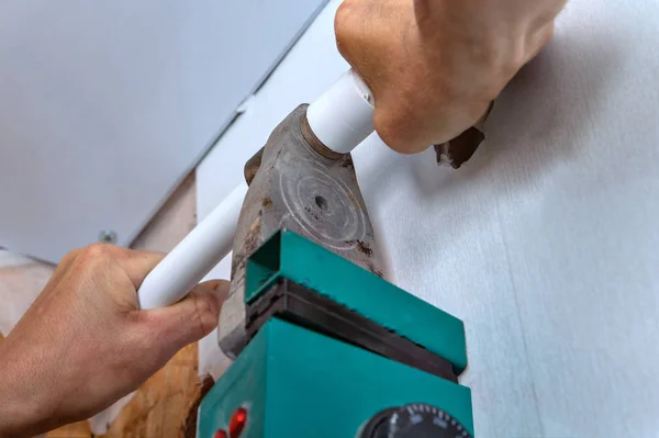 Man uses a heating machine for welding of polypropylene pipes.