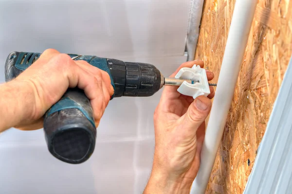 Verlijmen van klem voor pijpen op de muur met behulp van een schroevendraaier. — Stockfoto