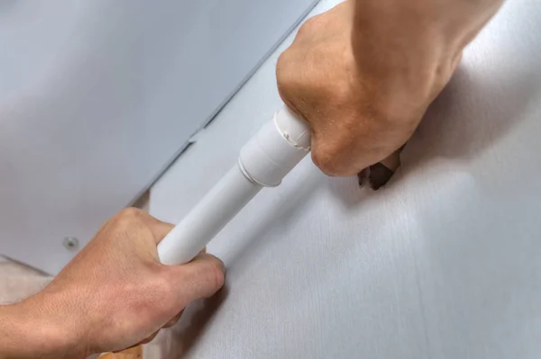 Ellerini duvarda, plastik su tesisatı borusu yüklemek yakın çekim.