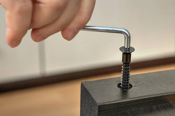 Screwing furniture screws in wooden board with hex wrench, close — Stock Photo, Image