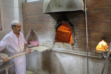 Baker bir kürek üzerinde hamur ile taş fırın duruyor.