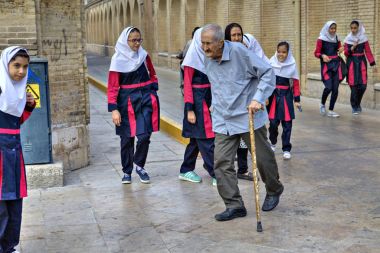 Yaşlı adam kız öğrenciler şehir sokak, Şiraz, Iran üzerinde yürür..