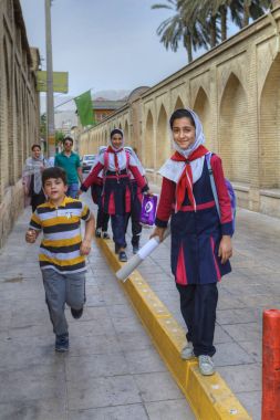 Iranian schoolgirl in uniform goes home after school. clipart