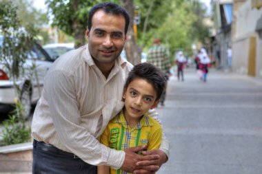 Adam şehir sokak, Şiraz, Iran bir fotoğrafçı için poz çocuk hugs.