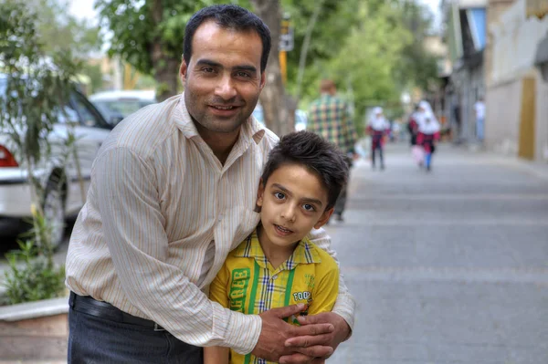 Mann umarmt Kind, das für einen Fotografen auf der Straße der Stadt posiert, shiraz, iran. — Stockfoto