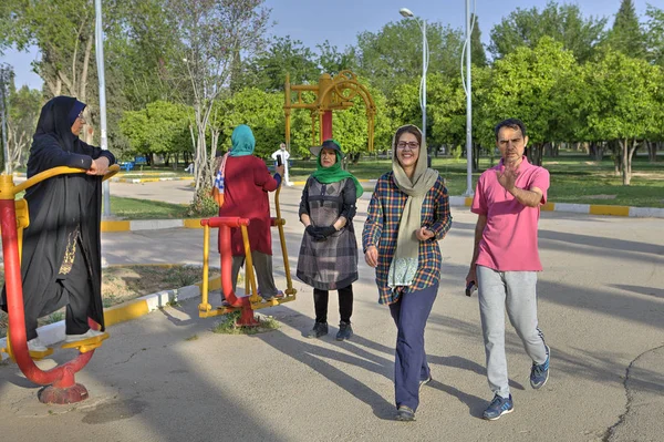 Mulheres muçulmanas vestindo hijabs fazem exercícios matinais em playground ao ar livre, Shiraz, Irã . Fotografias De Stock Royalty-Free