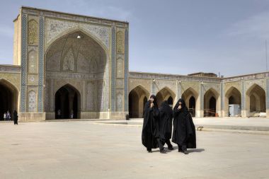Iranian women wearing black islamic dresses in inner courtyard Mosque, Shiraz, Iran clipart