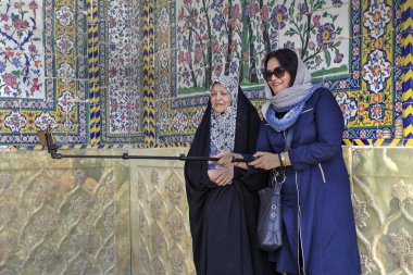 Two islamic women make selfie in courtyard of the mosque, Shiraz, Iran clipart