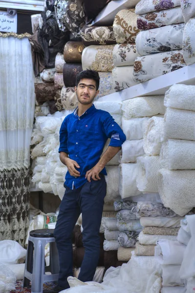 Genç İran satıcı doku Tekstil Dükkanı şehir çarşı, Şiraz, İran ' standları. — Stok fotoğraf