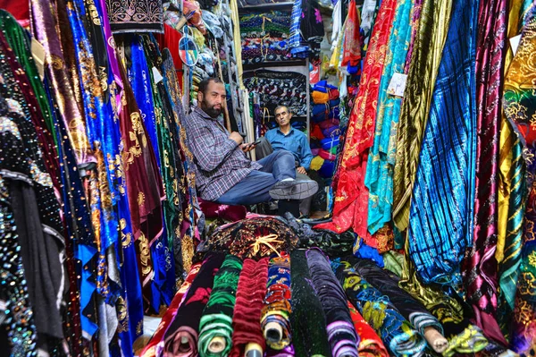 Tejidos del vendedor iraní sentado en la tienda de textiles del mercado de la ciudad, Shiraz, Irán . — Foto de Stock