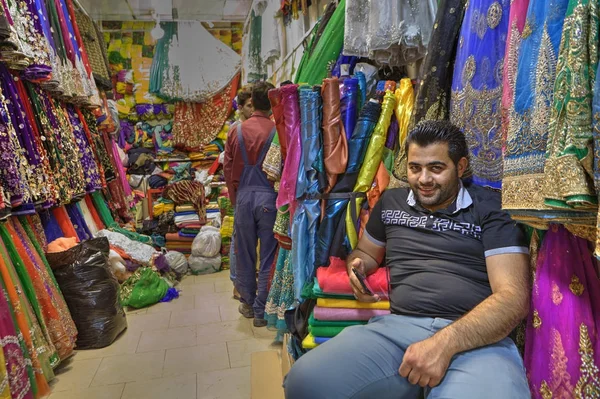 Vendedor de tela iraní sonríe a los turistas cuando espera a los compradores, Shiraz, Irán . — Foto de Stock