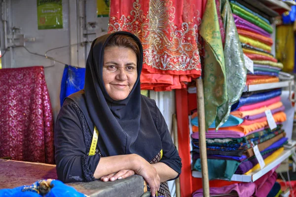 Uma mulher iraniana madura no hijab vende têxteis no bazar, Shiraz, Irão . — Fotografia de Stock