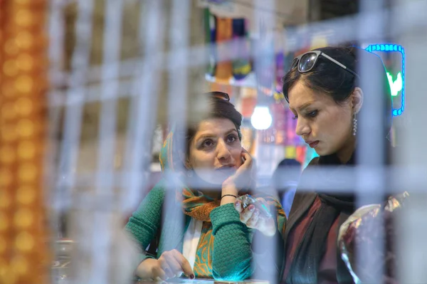 Two Iranian young women talking in shop inside bazaar, Shiraz, Iran. — Stock Photo, Image