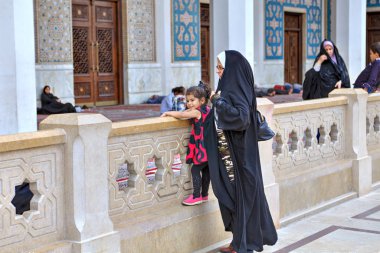 Müslüman kadının elini kolunu sallaya Camii avlusunda küçük kız, Şiraz, Iran ile dönüyor.