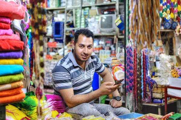 Vendedor de têxteis posando para fotógrafo sentado em sua loja, Shiraz, Irã . — Fotografia de Stock