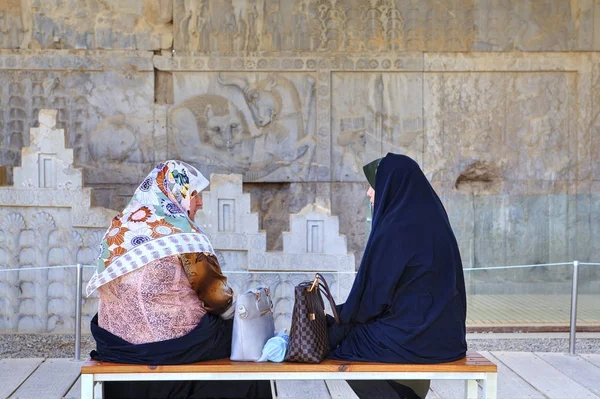 Mulheres muçulmanas conversando enquanto sentadas em um banco no museu de Persépolis perto de Shiraz, no Irã . — Fotografia de Stock