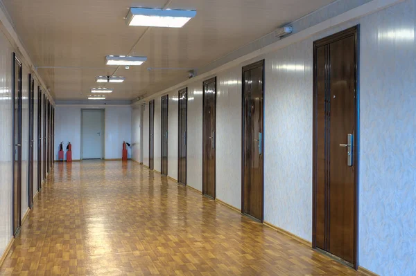 Corredor de escritório vazio com muitas portas de madeira vermelha escura . — Fotografia de Stock