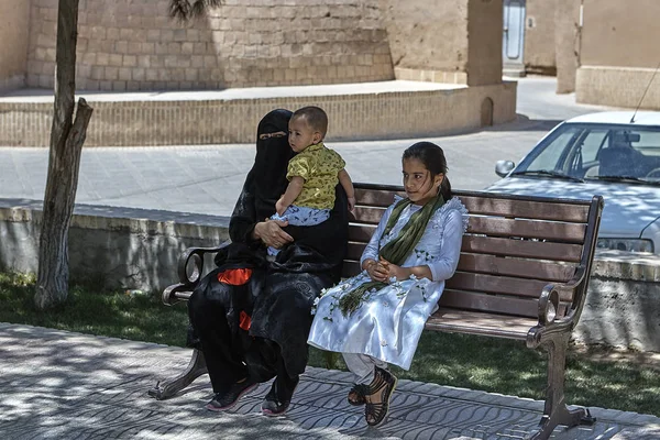 Mulher em roupas islâmicas senta-se no banco com dois filhos . — Fotografia de Stock