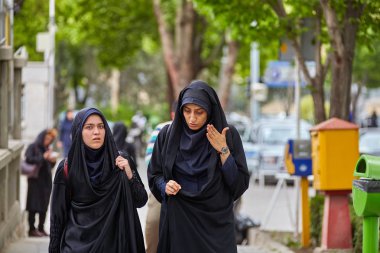 Muslim women in Islamic veil talking on street, Isfahan, Iran. clipart