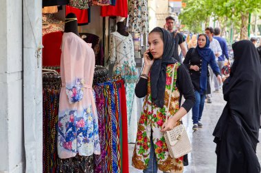 Kız parlak kıyafetleri, Isfahan, Iran ile salonu yakınındaki smartphone kullanır.