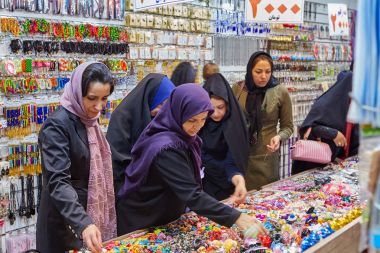Muslim women wearing obligatory headscarf, choose jewelry in street shop, Isfahan, Iran. clipart