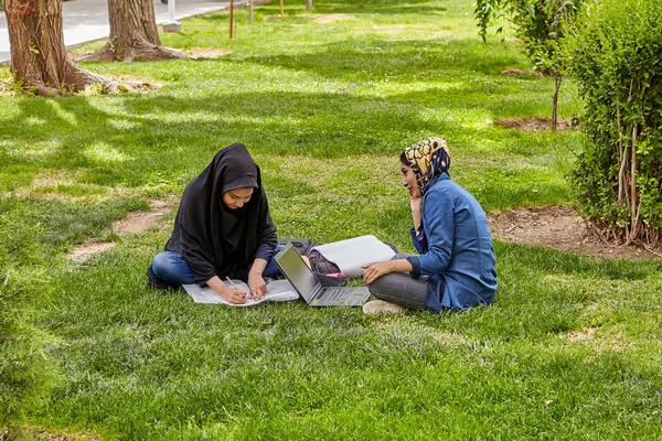 Mädchen bereiten sich auf den Unterricht auf dem Rasen im Park vor, isfahan, iran. — Stockfoto