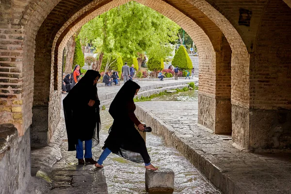 Молодые иранские женщины прыгают через воду под мостом, Исфахан, Иран . — стоковое фото