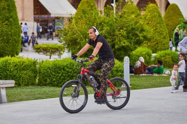 Kulaklıklı İranlı adam parkta bisiklet sürüyor, İsfahan, İran