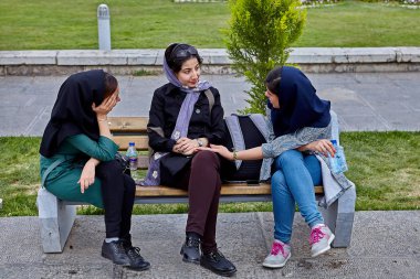 Isfahan, Iran - 24 Nisan 2017: Hijabs üç oldukça İranlı kadın parkta bir bankta oturup bir şey tartışmak.
