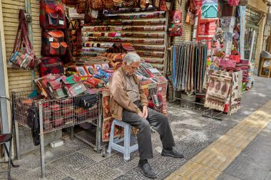 Isfahan, Iran - 24 Nisan 2017: piyasada Hatıra Eşyası satan bir İran adam çadırını uyuyor.