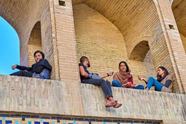 Young people rest in arched niches of bridge, Isfahan, Iran. clipart