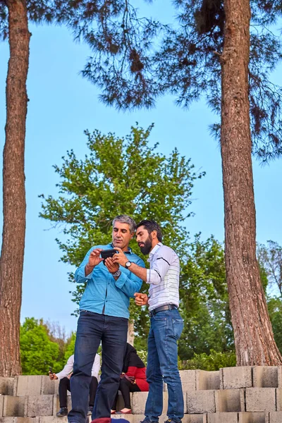 Deux hommes iraniens visionnent des images à l'écran d'un appareil mobile, Ispahan, Iran . — Photo