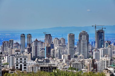 Skyscrapers on hillside and mountains in distance, Tehran, Iran. clipart