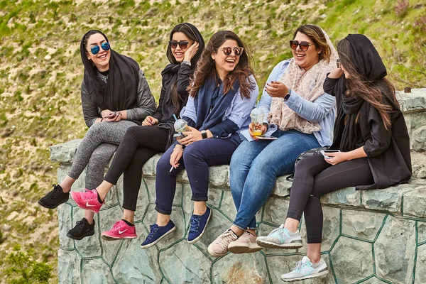 Iranian women laugh and drink cocktails in park, Tehran, Iran.