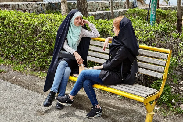 Zwei iranische frauen sitzen auf bank im park, tehran, iran. — Stockfoto
