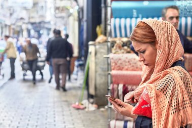Bir genç kadın akıllı telefon pazarında, Tahran, Iran kullanır..