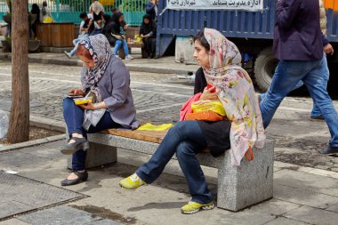 Hijabs'de iki İranlı kız Tehran sokak bankta oturmak.